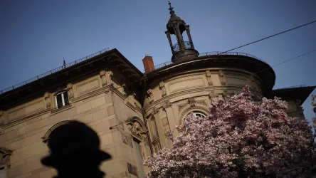 Ein historisches Gebäude mit einer Kuppel und einer Laterne. Im Vordergrund blühen pinke Blumen.