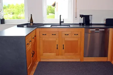 Moderne Küche mit Holzschränken, Schieferarbeitsfläche und Edelstahlgeräten (Spülmaschine).