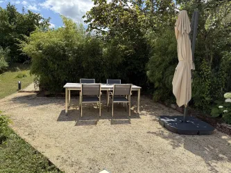 Essplatz im Freien, mit Sonnenschirm und Weber Grill.