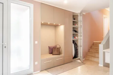 Ein moderner Eingangsbereich mit einem eleganten Schuhregal und einer Sitznische. Die Wände sind in hellen Farben gehalten und der Raum ist gut beleuchtet.