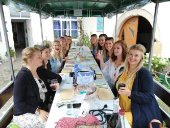 Eine fröhliche Gruppe von Frauen sitzt an einem gedeckten Tisch. Sie genießen Getränke und verbringen eine schöne Zeit zusammen.