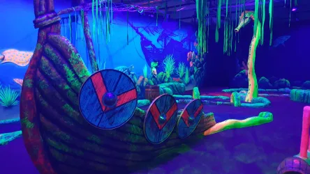 Eine fantasievolle Unterwasserwelt mit bunten, leuchtenden Elementen. Im Vordergrund sind ein Boot und verschiedene Pflanzen in lebhaften Farben zu sehen.