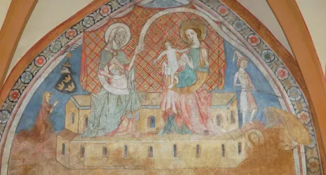 Ein kunstvolles Wandgemälde zeigt heilige Figuren in einer religiösen Darstellung. Die Farben sind sanft und verleihen der Szene eine historische Atmosphäre.