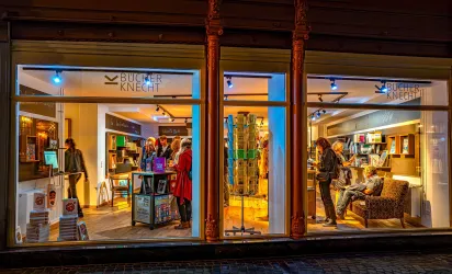 Ein Buchladen mit gemütlicher Atmosphäre, in dem mehrere Kunden stöbern. Im Hintergrund sind Regale mit Büchern und ein einladender Sitzbereich zu sehen.