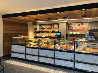 Eine moderne Bäckerei mit einem ansprechend gestalteten Verkaufsbereich. Es sind verschiedene frisch gebackene Brötchen und Gebäcksorten ausgestellt.