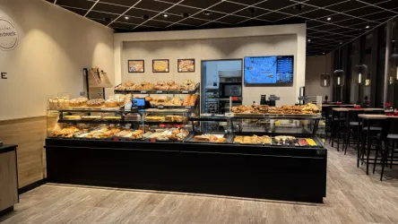 Ein modernes Café mit einer ansprechenden Auswahl an Backwaren und Süßigkeiten. Die Auslage ist gut beleuchtet und einladend.