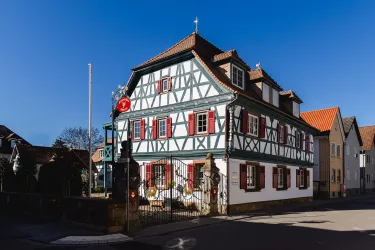 Ein historisches Fachwerkhaus mit grünen und roten Akzenten. Die klare blaue Himmel bietet einen schönen Kontrast zur Architektur.