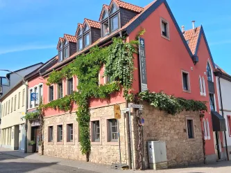 Ein charmantes Gebäude mit roter Fassade und begrünten Wänden. Die Architektur kombiniert moderne und traditionelle Elemente.