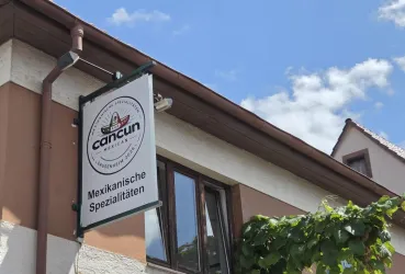 Ein Schild eines Restaurants mit dem Namen "Cancun". Es wird auf mexikanische Spezialitäten hingewiesen.
