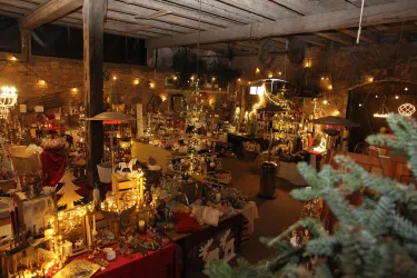 Ein festlich dekorierter Raum mit vielen leuchtenden Lichtern und handgefertigten Weihnachtswaren. Der Innenraum hat eine gemütliche Atmosphäre und erinnert an einen Weihnachtsmarkt.