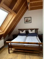 Ein gemütliches Schlafzimmer mit zwei Betten und hölzernen Wänden. Die Dachfenster bieten viel Tageslicht und Blick ins Freie.