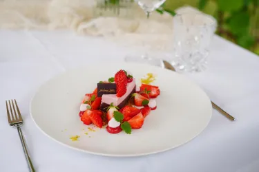 Ein schöner Dessertteller mit frischen Erdbeeren und einer rosa Creme. Dekoriert mit Schokolade und Minze, perfekt für einen besonderen Anlass.