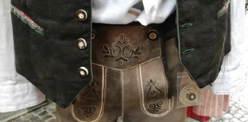 Ein traditionelles bayerisches Outfit mit einer eleganten Weste und Lederhosen. Die Hose ist kunstvoll verziert und zeigt typische Muster.