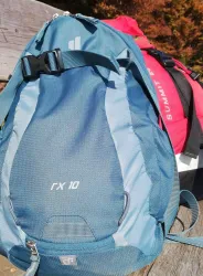 Zwei Rucksäcke auf einer Holzoberfläche. Der vordere Rucksack ist blau und der hintere rot.