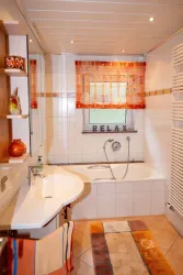 Ein modernes Badezimmer mit einer Badewanne und einem großen Spiegel. Dazu gehören farbige Vorhänge und ein Teppich, der eine entspannende Atmosphäre schafft.