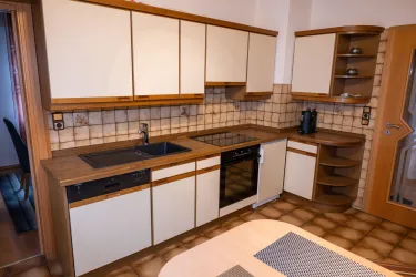 Eine moderne Küche mit hellen Schränken und einer Holzarbeitsfläche. Die Geräte und Spüle sind gut integriert und die Wände sind mit weißen Fliesen dekoriert.