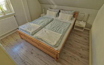 Gemütliches Schlafzimmer mit einem Doppelbett. Die Wände sind hell gestrichen und es gibt viel Tageslicht.