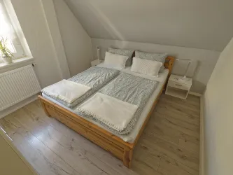 Gemütliches Schlafzimmer mit einem Doppelbett. Die Wände sind hell gestrichen und es gibt viel Tageslicht.
