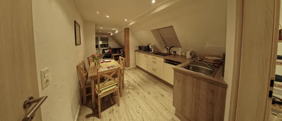 Eine moderne Küche mit einem Esstisch und Stühlen. Der Raum ist hell erleuchtet und hat eine gemütliche Atmosphäre.