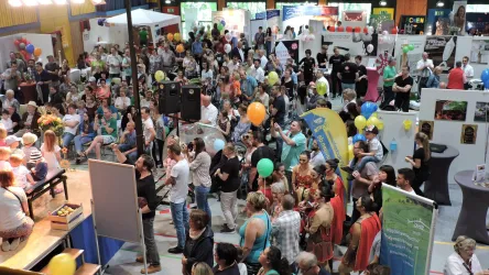 Eine große Menschenmenge bei einer Veranstaltung. Viele Besucher stehen und schauen sich die Stände an.