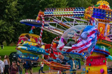 Ein bunter Freizeitpark mit aufregenden Fahrgeschäften. Menschen stehen in der Nähe und genießen die fröhliche Atmosphäre.