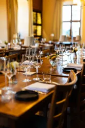 Ein eleganter Essbereich mit einem langen Holztisch. Es gibt Gläser und dekorative Blumen in der Mitte.