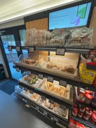 Ein Bäckereiregal mit verschiedenen Brötchen und Gebäck. Die Produkte sind ordentlich präsentiert und in transparenten Kästen geschützt.