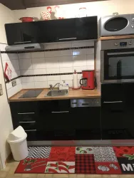 Eine moderne Küche mit schwarzen Möbeln und Holzarbeitsplatte. Der Boden ist mit einem bunten Teppich dekoriert.