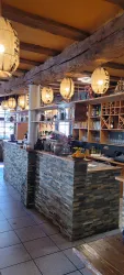 Eine einladende Bar mit einer Steinoberfläche und warmem Licht. Im Hintergrund sind Regale mit Getränken und Dekorationen zu sehen.