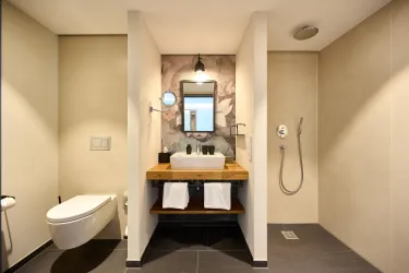Ein modernes Badezimmer mit einer Dusche und einem ansprechenden Waschbecken auf einem Holztisch. Die Wände sind elegant gestaltet und schaffen eine angenehme Atmosphäre.