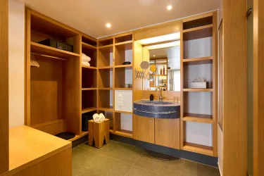 Ein modernes Badezimmer mit Holzregalen und einem runden Waschbecken. Das Licht ist hell und schafft eine einladende Atmosphäre.