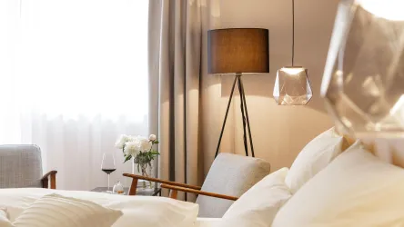 Ein modernes Schlafzimmer mit einem bequemen Bett und stilvollen Möbeln. Eine Stehlampe und dekorative Elemente schaffen eine gemütliche Atmosphäre.