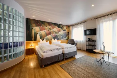 Ein modernes Hotelzimmer mit zwei Betten und einem attraktiven Dekor. Helle Wände und große Fenster sorgen für eine freundliche Atmosphäre.
