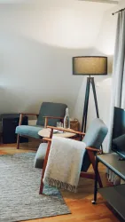 Ein gemütlicher Bereich des Hotelzimmers mit zwei bequemen Sesseln und einem modernen Stehlampe. Der Raum hat einen warmen Holzboden.