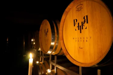 Fasslager mit Holzfässern in einem Weinunternehmer. Sanftes Licht einer Kerze, das eine gemütliche Atmosphäre schafft.