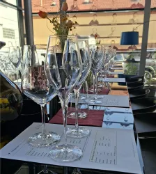 Eine Gruppe eleganter Sektgläser steht auf einem Tisch. Im Hintergrund spiegeln sich runde Wandobjekte.