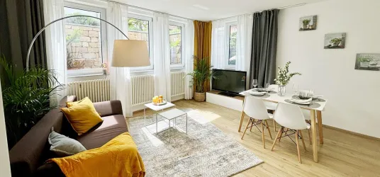 Geräumiges Wohnzimmer mit modernem Design und einer gemütlichen Couch. Ein Essbereich mit Tisch und Stühlen vervollständigt den Raum.
