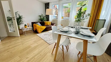 Ein modernes Wohnzimmer mit einem gemütlichen Sofa und einem Esstisch. Der Raum ist hell erleuchtet und durch große Fenster gut belüftet.