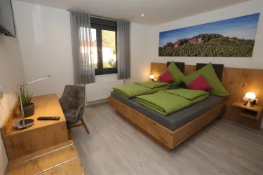 Ein modernes Schlafzimmer mit einem gemütlichen Doppelbett und bunten Kissen. Der Raum verfügt über ein Fenster mit Blick nach draußen und eine stilvolle Einrichtung.