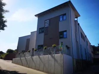 Ein modernes Gebäude mit der Aufschrift "Fels". Es hat mehrere Fenster und eine helle Fassade.