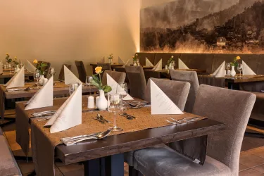 Ein elegantes Restaurant mit schön gedeckten Tischen und modernen Stühlen. Die Dekoration ist schlicht und ansprechend, mit frischen Blumen auf den Tischen.