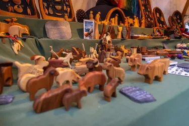 Eine Vielzahl von handgefertigten Holzfiguren ist auf einem Tisch ausgestellt. Die Figuren repräsentieren verschiedene Tiere und kunstvolle Designs.