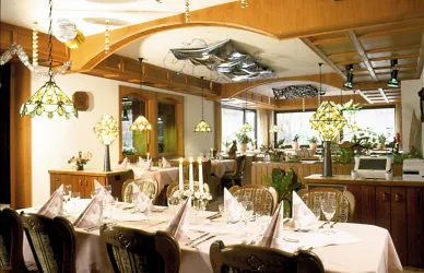 Ein elegantes Restaurant mit gedeckten Tischen und dekorativen Lampen. Der Raum ist warm und einladend gestaltet, ideal für ein schönes Essen.