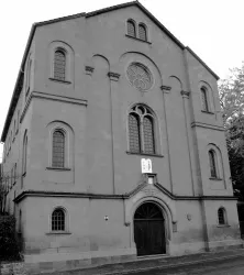 Eine beeindruckende Steinstruktur mit konservativem Design und großen Fenstern. Das Gebäude hat eine historische Ausstrahlung und befindet sich in einem ruhigen Umfeld.