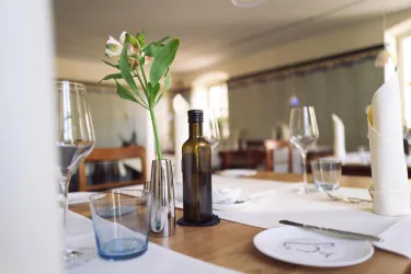 Ein eleganter Tisch in einem Restaurant, dekoriert mit einem Blumenstrauß und Glasware. Die Atmosphäre ist freundlich und einladend.