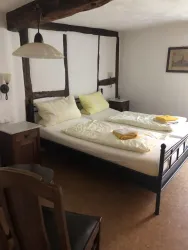 Ein gemütliches Zimmer mit einem Doppelbett und gelben Kissen. Holzdetails und eine warmfarbene Einrichtung verleihen dem Raum eine einladende Atmosphäre.