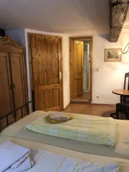 Ein gemütliches Zimmer mit zwei Einzelbetten und Holzdetails. Im Hintergrund sind Türen und ein Tisch zu sehen.