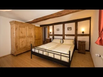 Ein gemütliches Schlafzimmer mit einem Doppelbett und Holzböden. Der Raum hat einen rustikalen Stil mit sichtbaren Balken und einem großen Kleiderschrank.
