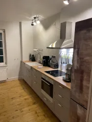 Eine moderne Küche mit Holzoberflächen und Edelstahl-Geräten. Die Wand ist in sanften Farben gestrichen und lässt viel Licht herein.