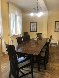 Ein einladender Essbereich mit einem großen Holztisch und schwarzen Stühlen. Helle Wände und Fenster sorgen für eine freundliche Atmosphäre.